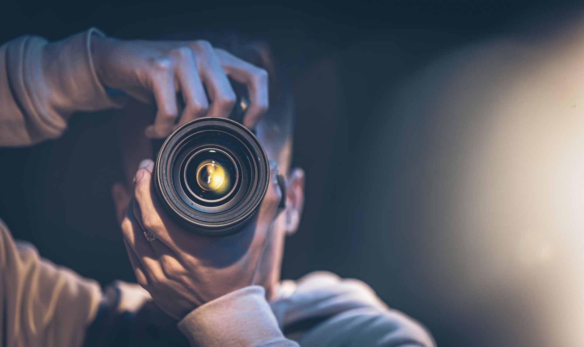 Un homme photographe avec un appareil photo prend une photo dans l’obscurité, l’espace de copie.